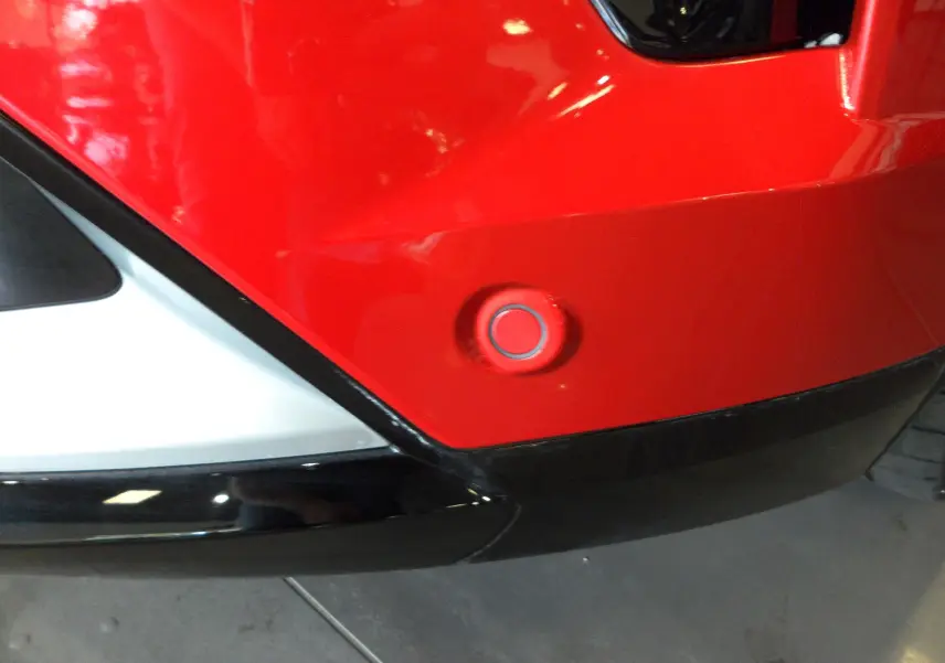 Détail du pare-chocs arrière rouge flamme du Renault Rafale 2025 avec capteur de stationnement circulaire.