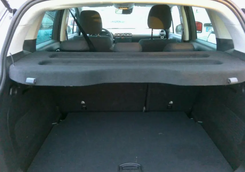 Vue intérieure du coffre et des sièges arrière d'une Citroën C3 Aircross gris foncé, avec tablette cache-bagages déployée.