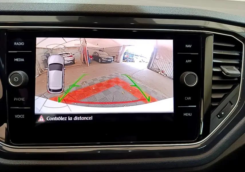 Écran tactile intérieur montrant la caméra de recul et l’aide au stationnement du Volkswagen T-Roc blanc.