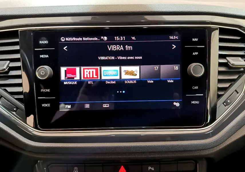Écran tactile central affichant les radios FM dans l’habitacle du Volkswagen T-Roc blanc, vue rapprochée frontale.