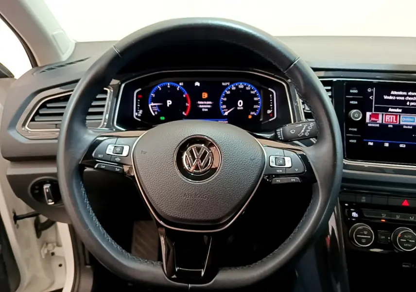 Vue rapprochée du volant cuir noir et du tableau de bord digital du Volkswagen T-Roc blanc 1.5 TSI 2020.
