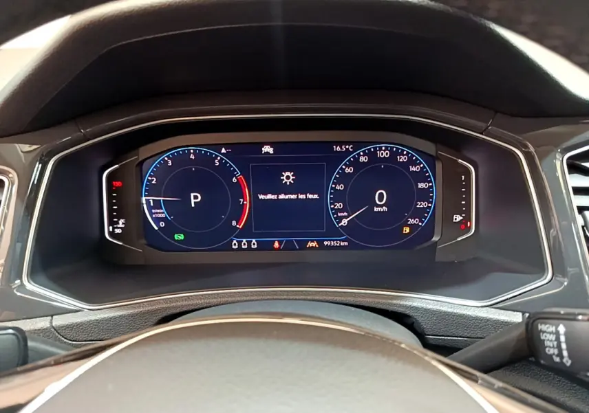 Vue rapprochée du tableau de bord numérique du Volkswagen T-Roc 1.5 TSI blanc, affichant la vitesse et le régime moteur.