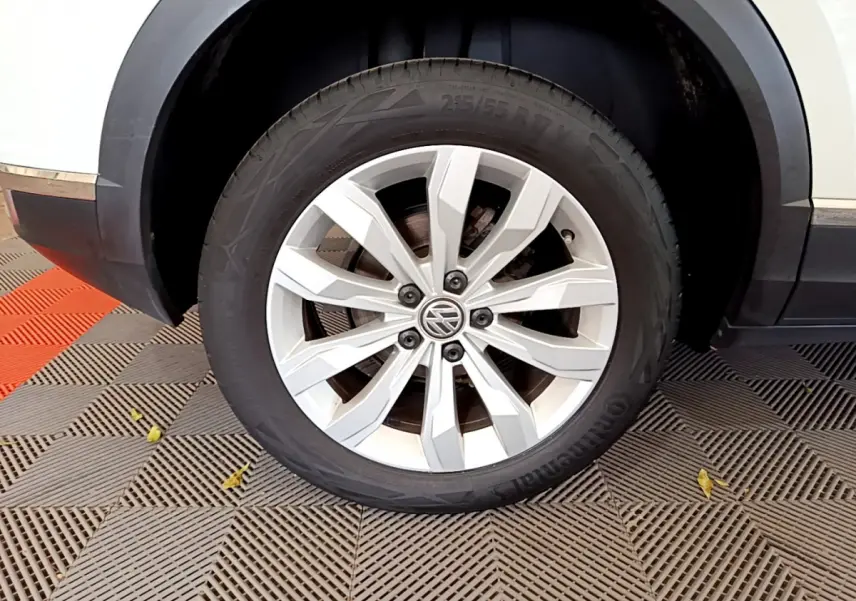 Gros plan sur la roue avant droite blanche du Volkswagen T-Roc 1.5 TSI 150 EVO CARAT DSG7 avec jante alliage argentée.