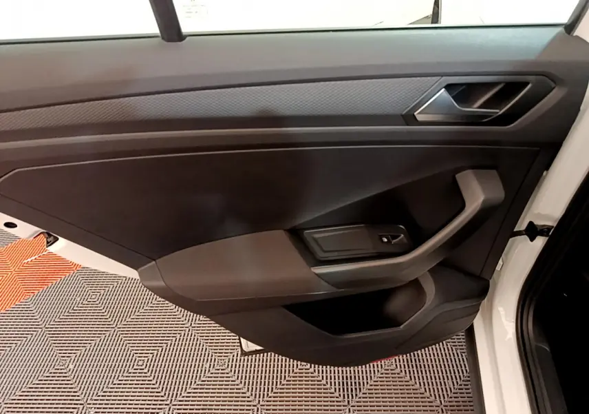 Vue intérieure de la porte avant droite noire du Volkswagen T-Roc blanc 2020 avec poignée et commande de vitre.