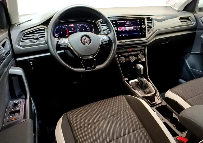 Vue intérieure côté conducteur du Volkswagen T-Roc 1.5 TSI blanc, volant cuir multifonctions et écran tactile central.