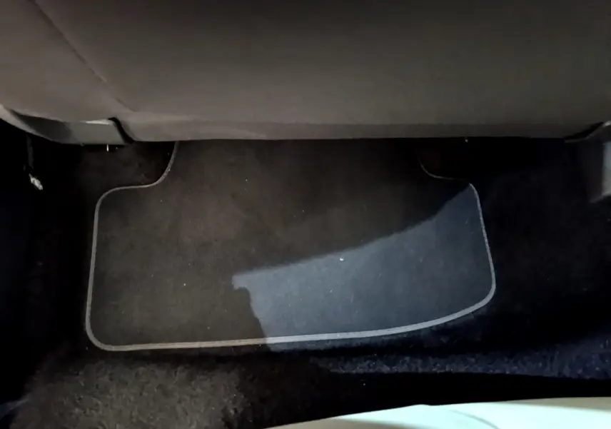 Tapis de sol noir sous le siège arrière d'un Volkswagen T-Roc blanc, vue intérieure au sol côté passager.