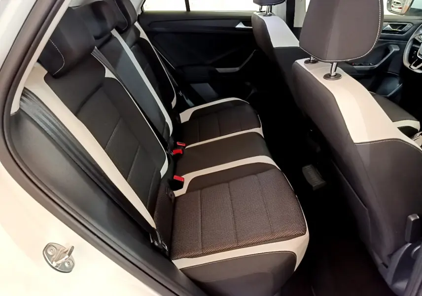 Vue intérieure côté gauche du Volkswagen T-Roc 1.5 TSI blanc, mettant en valeur la banquette arrière bicolore noire et beige.
