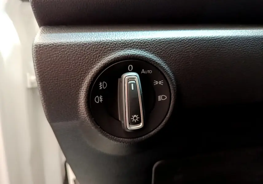 Gros plan sur le sélecteur d'éclairage noir du tableau de bord du Volkswagen T-Roc blanc, côté gauche.