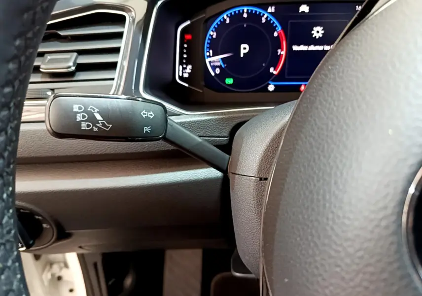 Gros plan sur le volant noir et le combiné d'instruments digital du Volkswagen T-Roc 1.5 TSI blanc, affichage multifonctions visible.