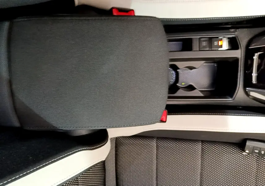 Vue plongeante sur l'accoudoir central noir et console beige du Volkswagen T-Roc 1.5 TSI 2020 avec porte-gobelets.