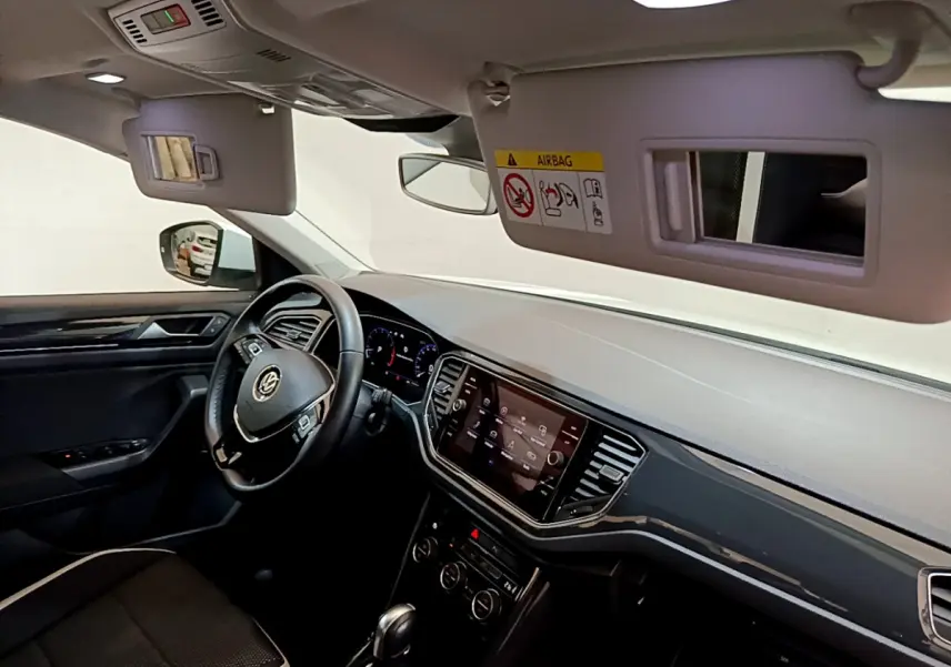 Intérieur du Volkswagen T-Roc 1.5 TSI 2020 vu côté conducteur, tableau de bord noir avec écran tactile et volant cuir.