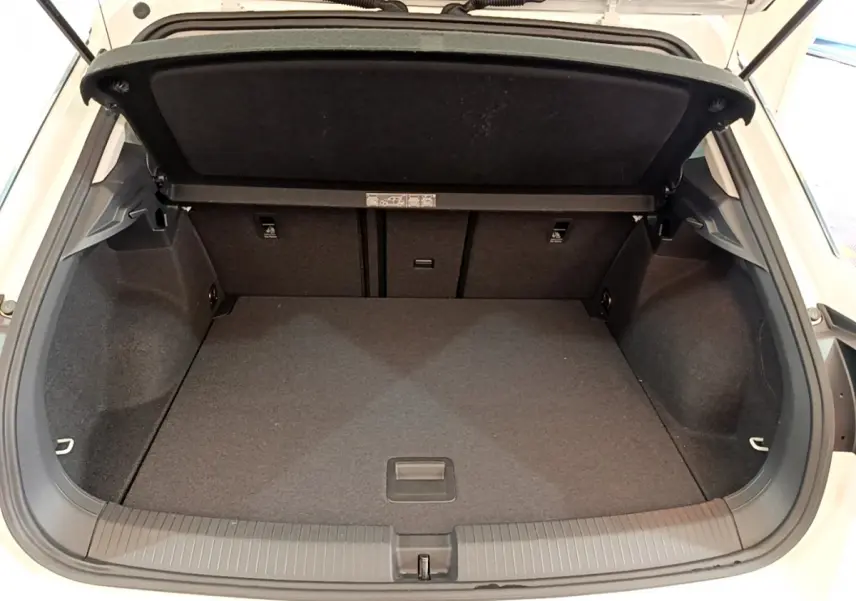 Coffre ouvert du Volkswagen T-Roc blanc, vue arrière montrant l’espace de chargement vide et la tablette de séparation.