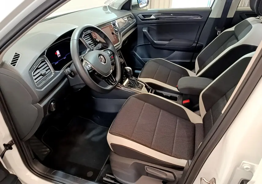 Intérieur avant droit du Volkswagen T-Roc blanc 2020, sièges bi-ton noirs et beige, tableau de bord moderne avec écran tactile.