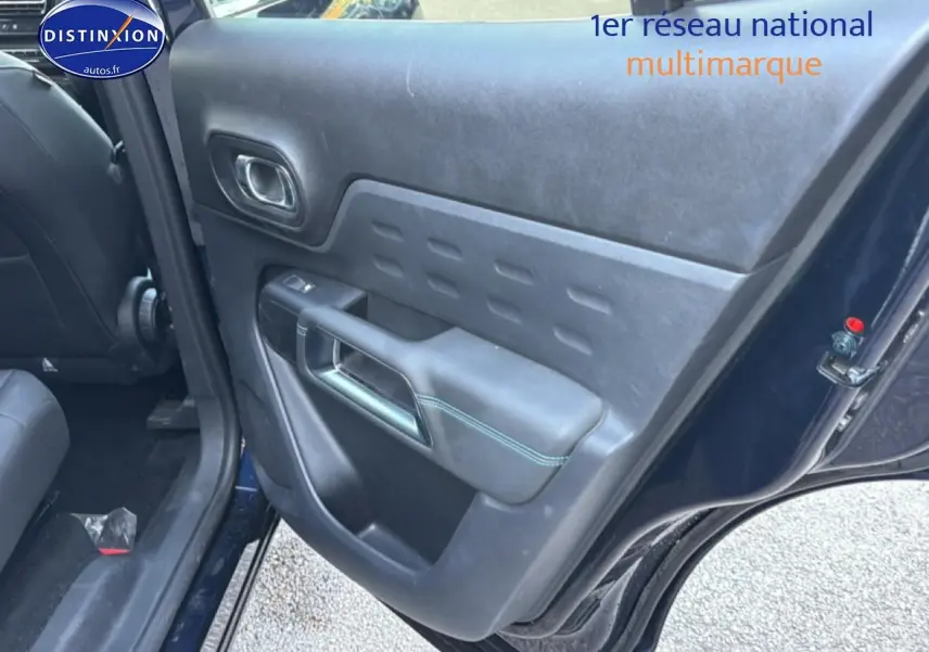 Vue intérieure du côté arrière gauche de la porte d’un Citroën C5 Aircross bleu eclipse avec accoudoir et commande de vitre.