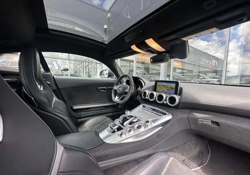 Intérieur noir du Mercedes AMG GT 2015 vu côté conducteur, avec console centrale alu et toit panoramique.