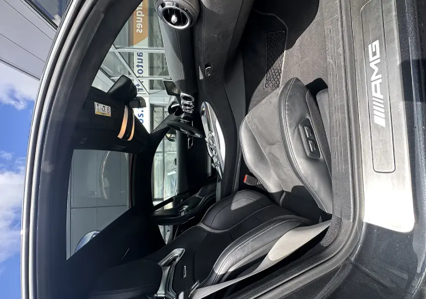 Intérieur noir du Mercedes AMG GT 2015 vu côté conducteur, avec sièges sport et seuil AMG éclairé.