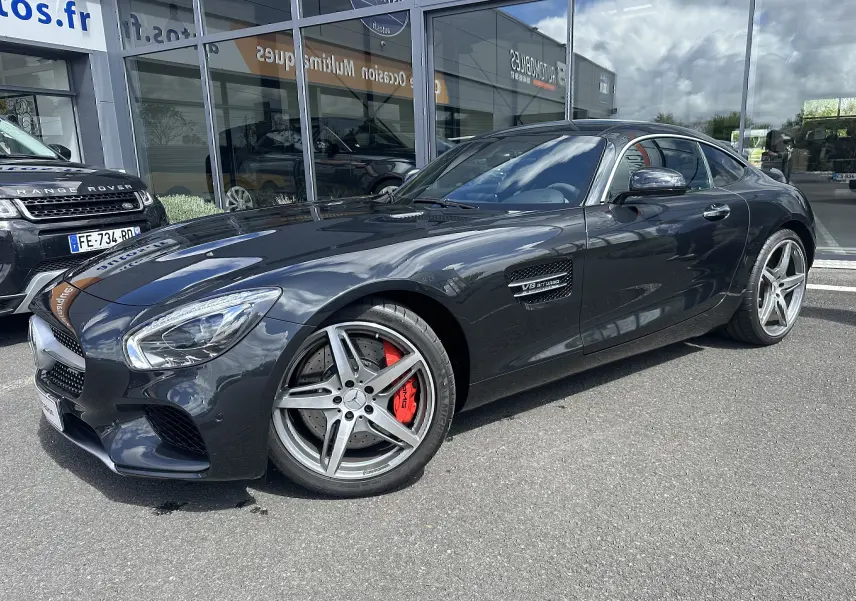 Mercedes AMG GT gris foncé vue 3/4 avant droit, jantes argentées et étriers de frein rouges visibles.