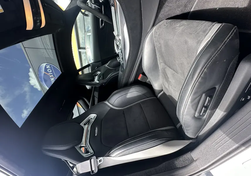 Vue intérieure du siège avant droit en cuir noir et alcantara du Mercedes AMG GT gris foncé, avec ceinture de sécurité visible.