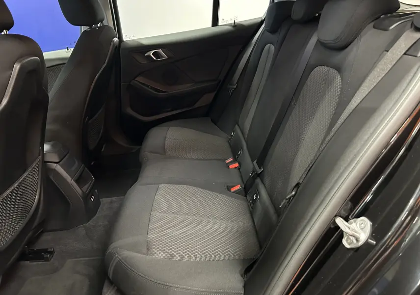 Vue intérieure côté droit des sièges arrière en tissu gris foncé d'une BMW Série 1 noire de 2023.