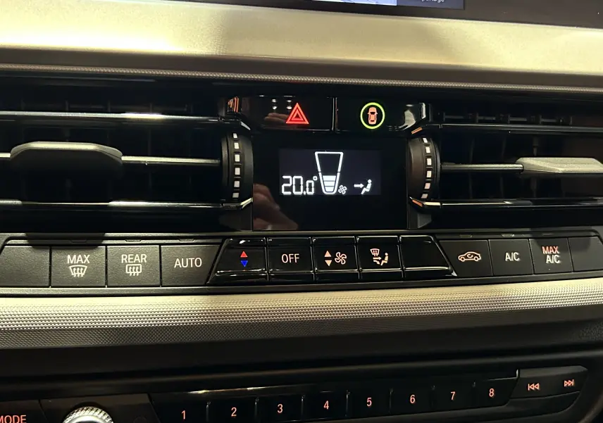 Gros plan sur la console centrale de la BMW Série 1 16d 2023, affichant la climatisation à 20°C avec commandes tactiles.