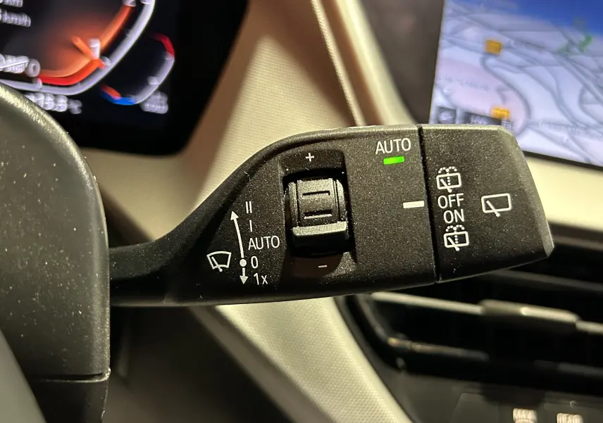 Gros plan sur la commande d’essuie-glace avec fonction auto activée dans l’habitacle d’une BMW Série 1 noire 2023.