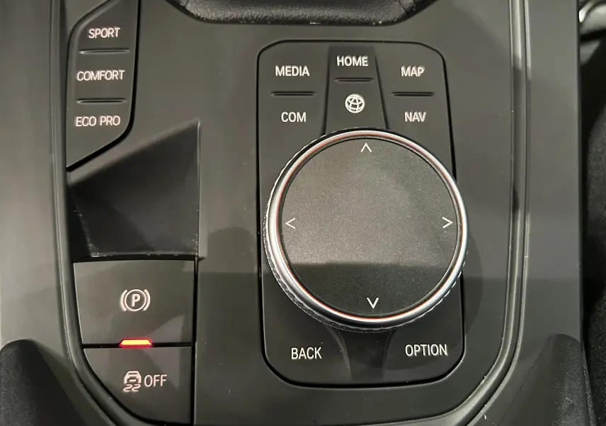 Gros plan sur la molette de commande centrale noire du BMW Série 1 16d 2023 avec boutons de mode de conduite et parking.