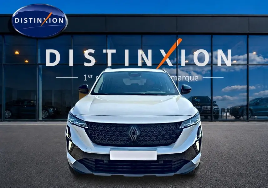 Renault Austral blanc nacré vu de face, avec calandre noire et logo Renault proéminent devant un showroom Distinxion.