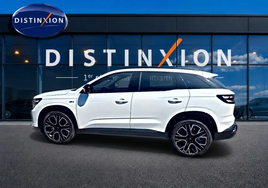 Profil droit du Renault Austral blanc nacré 2026 avec jantes alu noires et toit contrasté devant une vitrine Distinxion.