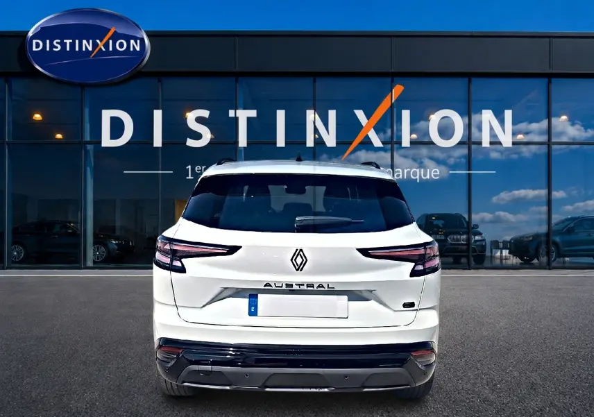 Vue arrière d'un Renault Austral blanc nacré 2026 avec feux LED et becquet arrière, devant une vitrine Distinxion.