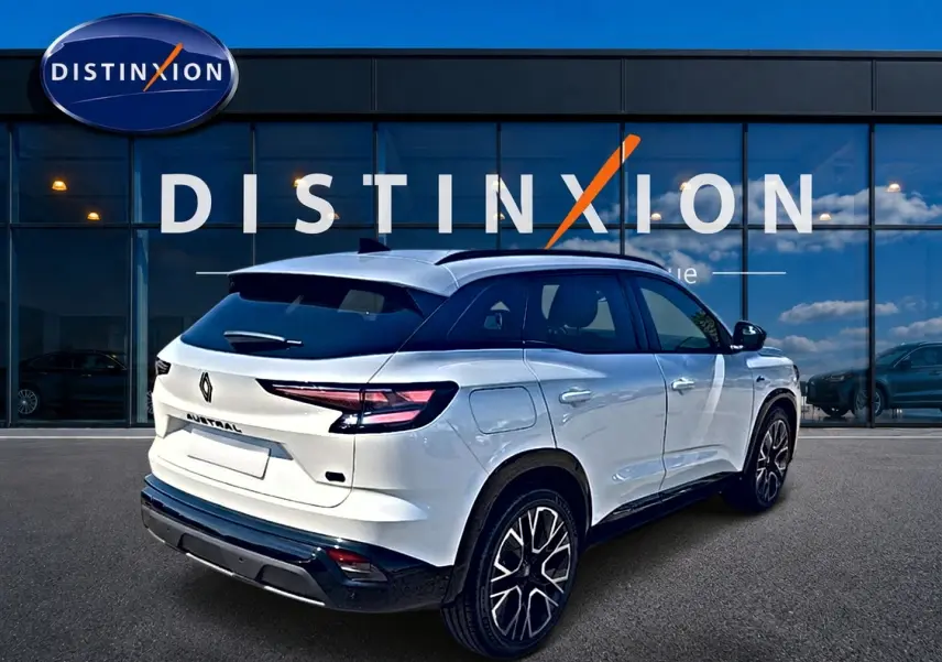 Vue 3/4 arrière droite du Renault Austral blanc nacré avec jantes alliage et toit noir devant une vitrine Distinxion.