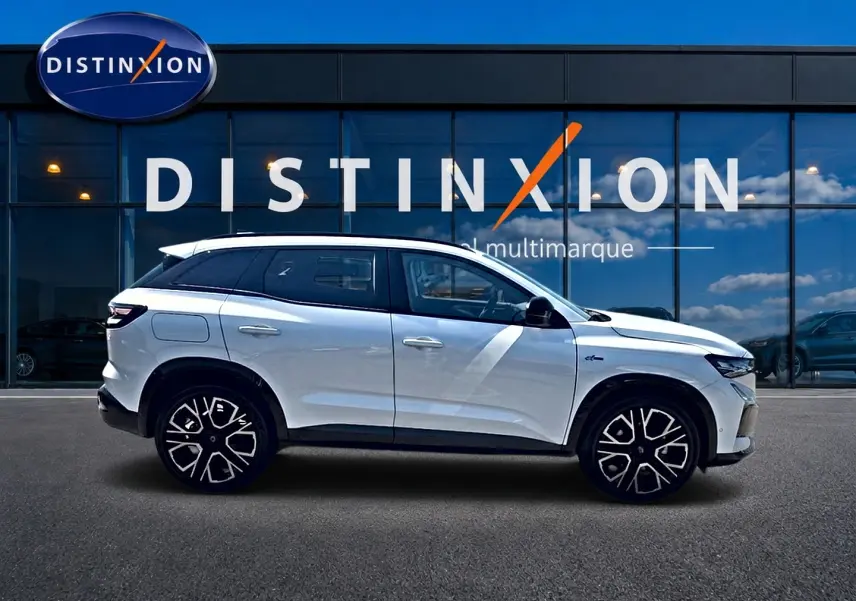 Renault Austral blanc nacré en profil droit, avec jantes alu et toit surélevé devant une vitrine Distinxion.