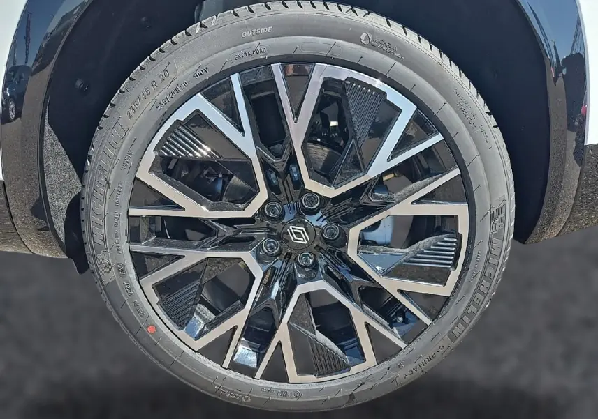 Gros plan sur la jante alu noire et argentée du Renault Austral blanc nacré, avec logo Renault au centre.