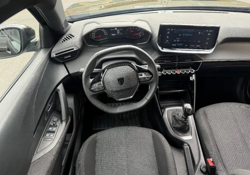 Vue intérieure frontale du Peugeot 2008 2025 noir perla, avec volant compact, tableau de bord numérique et boîte manuelle.