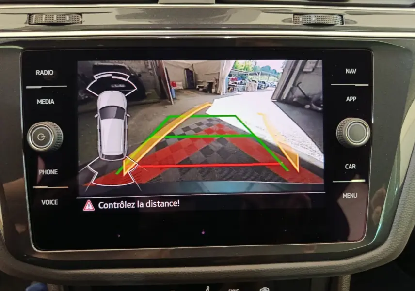 Écran tactile du Volkswagen Tiguan bleu montrant la caméra de recul avec guidage de trajectoire et alertes de distance.