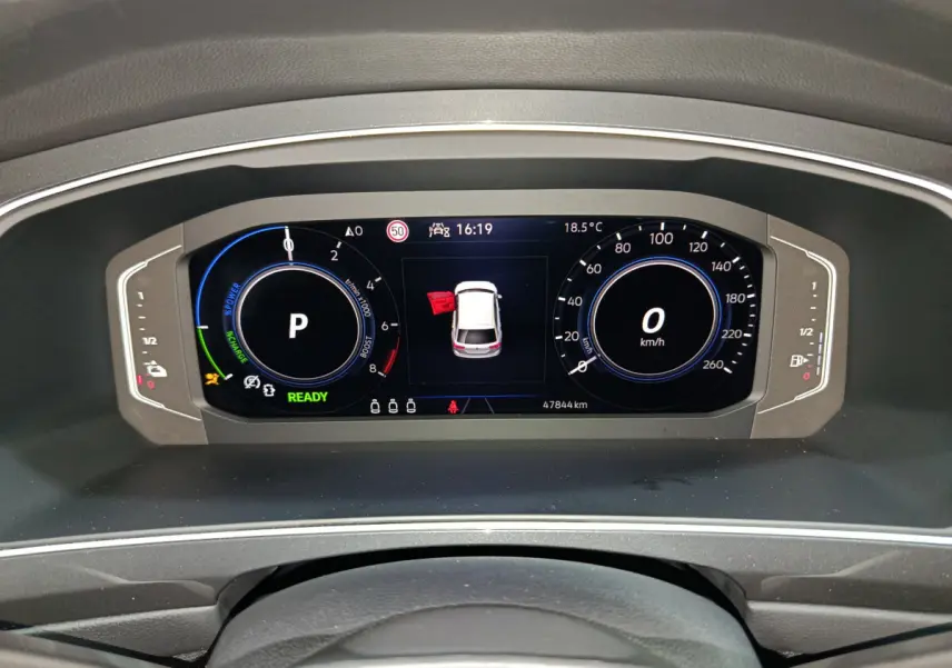 Tableau de bord numérique du Volkswagen Tiguan hybride bleu, affichant la vitesse à 0 km/h et porte ouverte côté gauche.