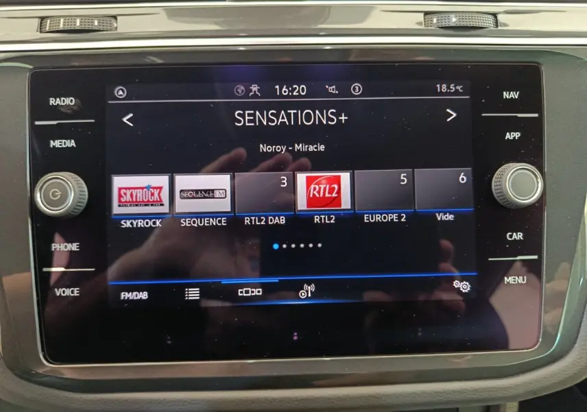 Écran tactile central du Volkswagen Tiguan bleu 2022 affichant les stations radio FM/DAB avec commandes latérales.