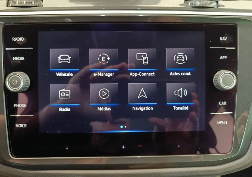 Écran tactile central du Volkswagen Tiguan 2022 affichant les menus multimédia et navigation, avec boutons latéraux visibles.