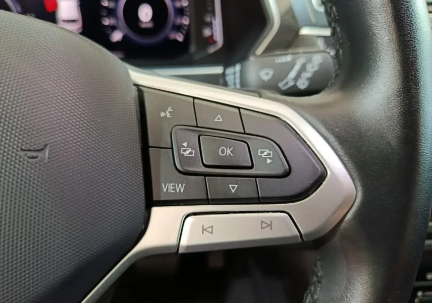 Gros plan sur les commandes multifonctions à droite du volant cuir du Volkswagen Tiguan bleu hybride 2022.