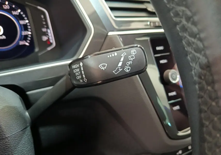 Gros plan sur la commande d'essuie-glace à gauche du volant dans l'habitacle du Volkswagen Tiguan hybride 2022.