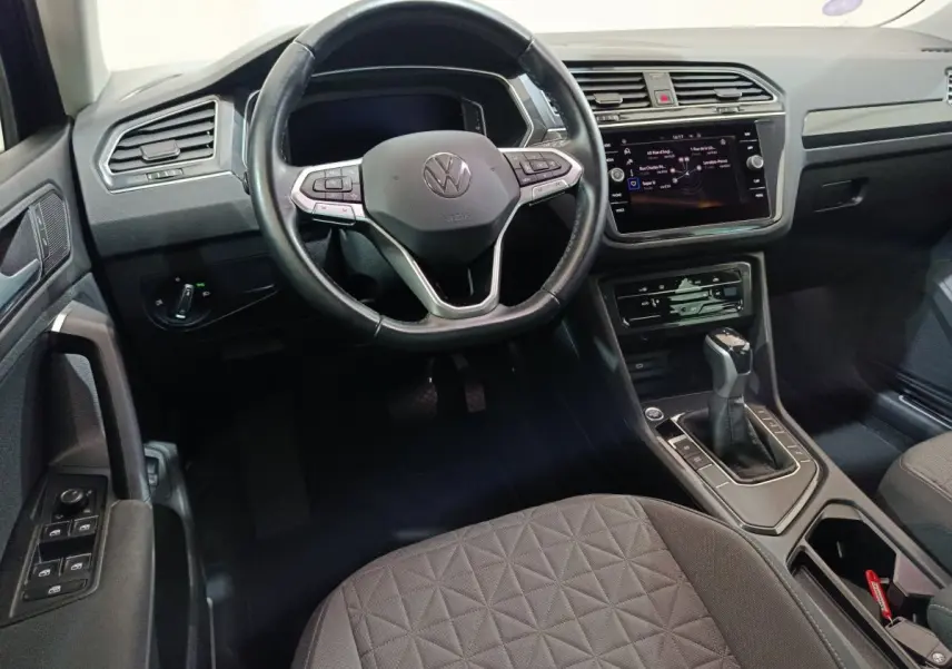 Intérieur avant du Volkswagen Tiguan bleu 2022, vue du poste de conduite avec volant cuir et écran tactile central.