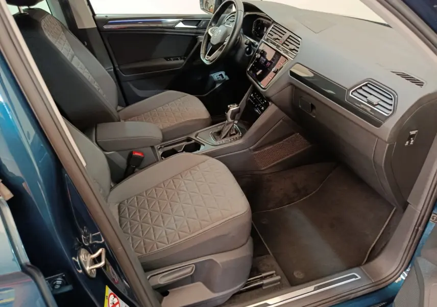 Intérieur avant droit du Volkswagen Tiguan bleu 2022 avec sièges gris et tableau de bord moderne tactile