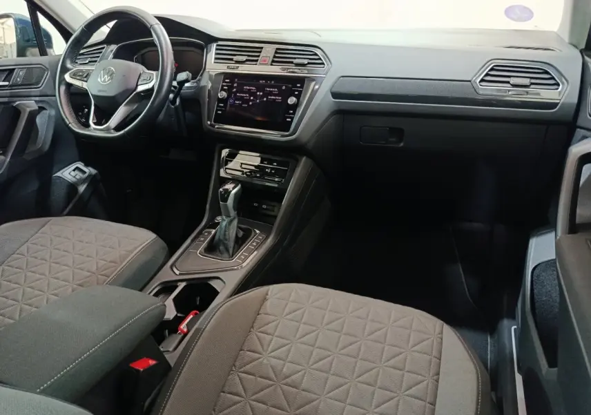 Intérieur avant du Volkswagen Tiguan bleu 2022, vue côté conducteur, tableau de bord et console centrale modernes.