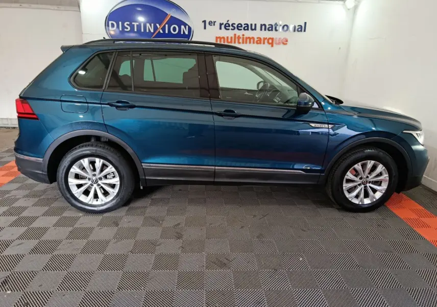 Profil droit d'un Volkswagen Tiguan bleu 2022 hybride rechargeable, avec jantes alliage et badges distinctifs sur ailes.