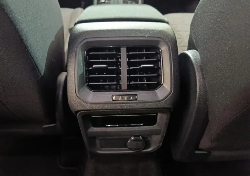 Bouche d'aération arrière et prise 12V entre les sièges noirs du Volkswagen Tiguan hybride rechargeable 2022.