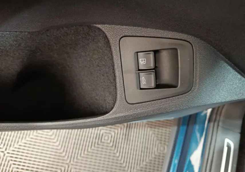 Gros plan sur les boutons d'ouverture du coffre et de la trappe à carburant côté conducteur du Volkswagen Tiguan bleu hybride 2022.