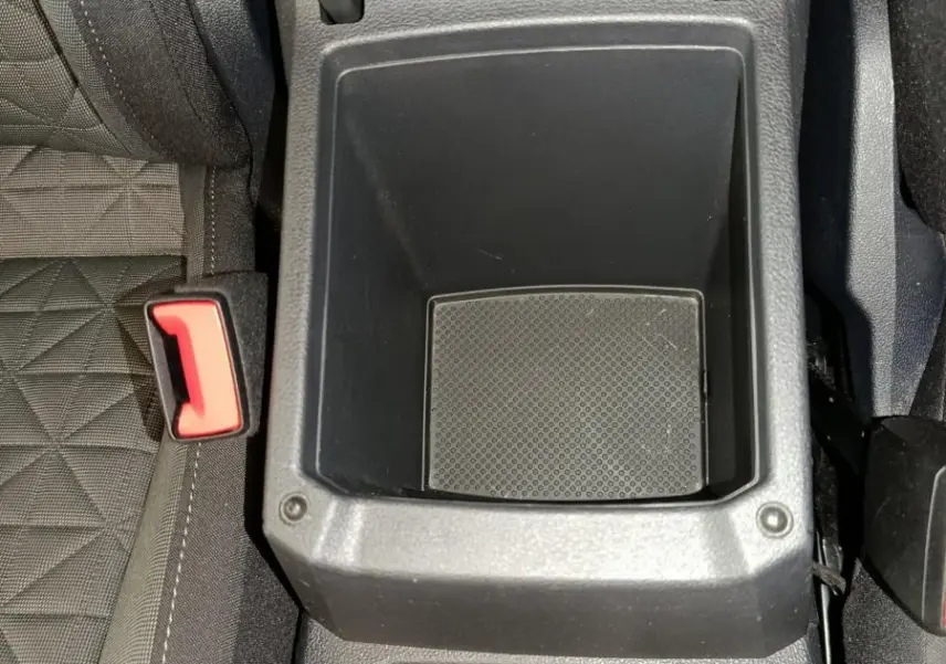 Vue plongeante sur la console centrale noire du Volkswagen Tiguan bleu, avec porte-gobelets et rangement vide.