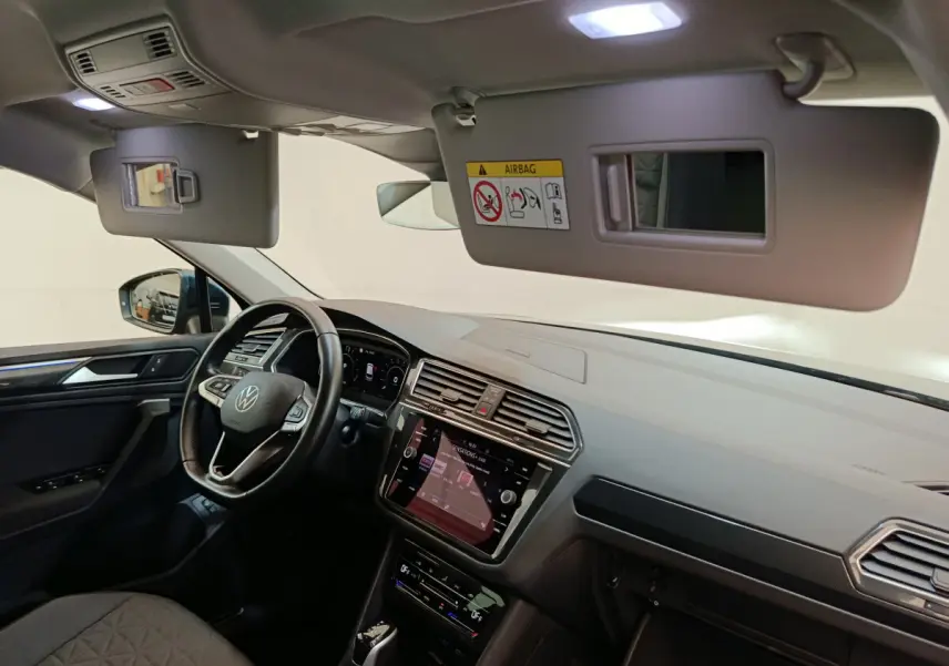 Vue intérieure côté conducteur du tableau de bord et volant cuir du Volkswagen Tiguan bleu 2022 hybride rechargeable.