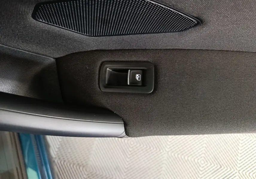 Bouton de commande de lève-vitre sur la portière côté gauche d'un Volkswagen Tiguan bleu hybride rechargeable.