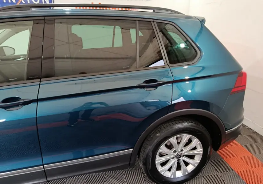 Vue latérale droite du Volkswagen Tiguan 1.4 eHybrid bleu 2022, mettant en valeur la roue arrière et les vitres teintées.