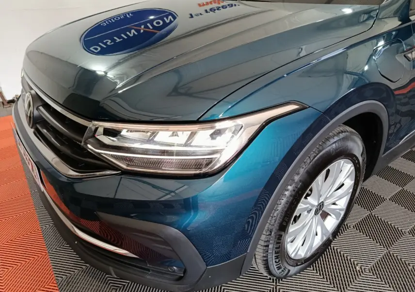 Vue 3/4 avant droit du Volkswagen Tiguan bleu 2022 avec phares LED et jante alliage visible.